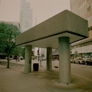 Street photo of a man framed by a bus stop taken with color modifying film